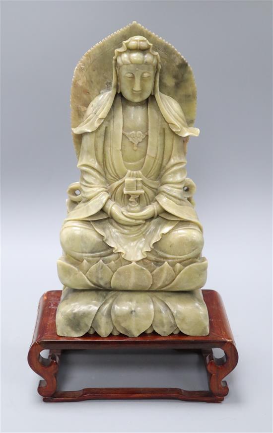 A seated soapstone figure of Guanyin with wood stand Figure excluding base H.33cm